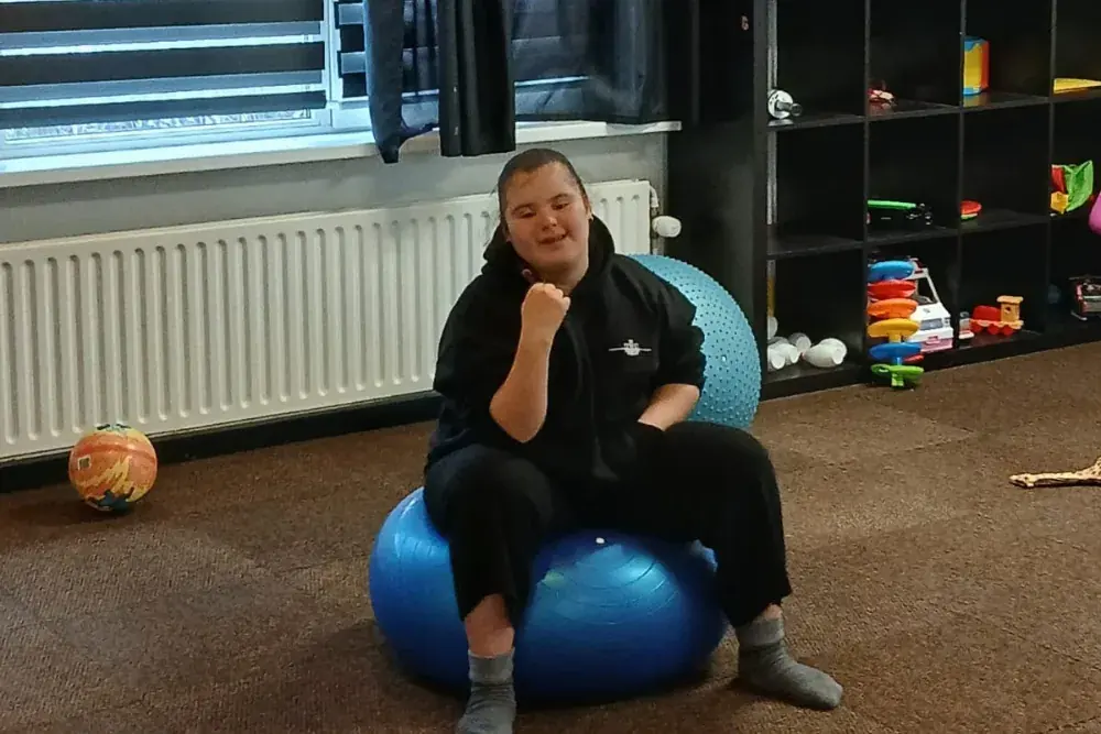 Iemand zit op een grote blauwe gymbal in de beweegruimte.