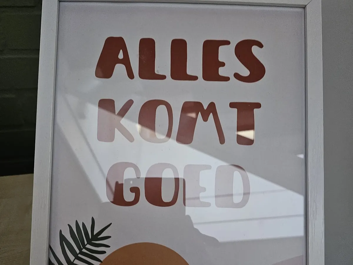Een poster in een witte lijst: „Alles komt goed.”