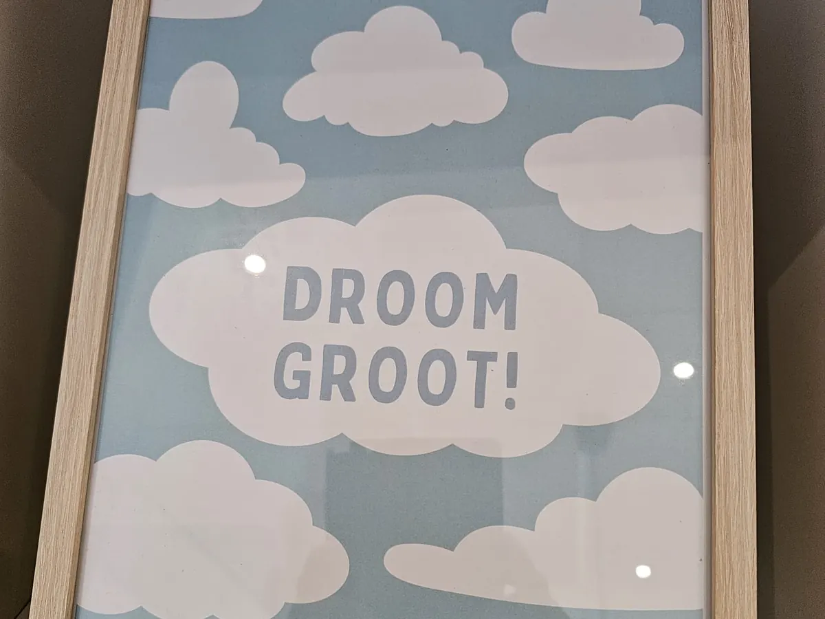 Een lichtblauwe poster met wolken: „Droom groot!”
