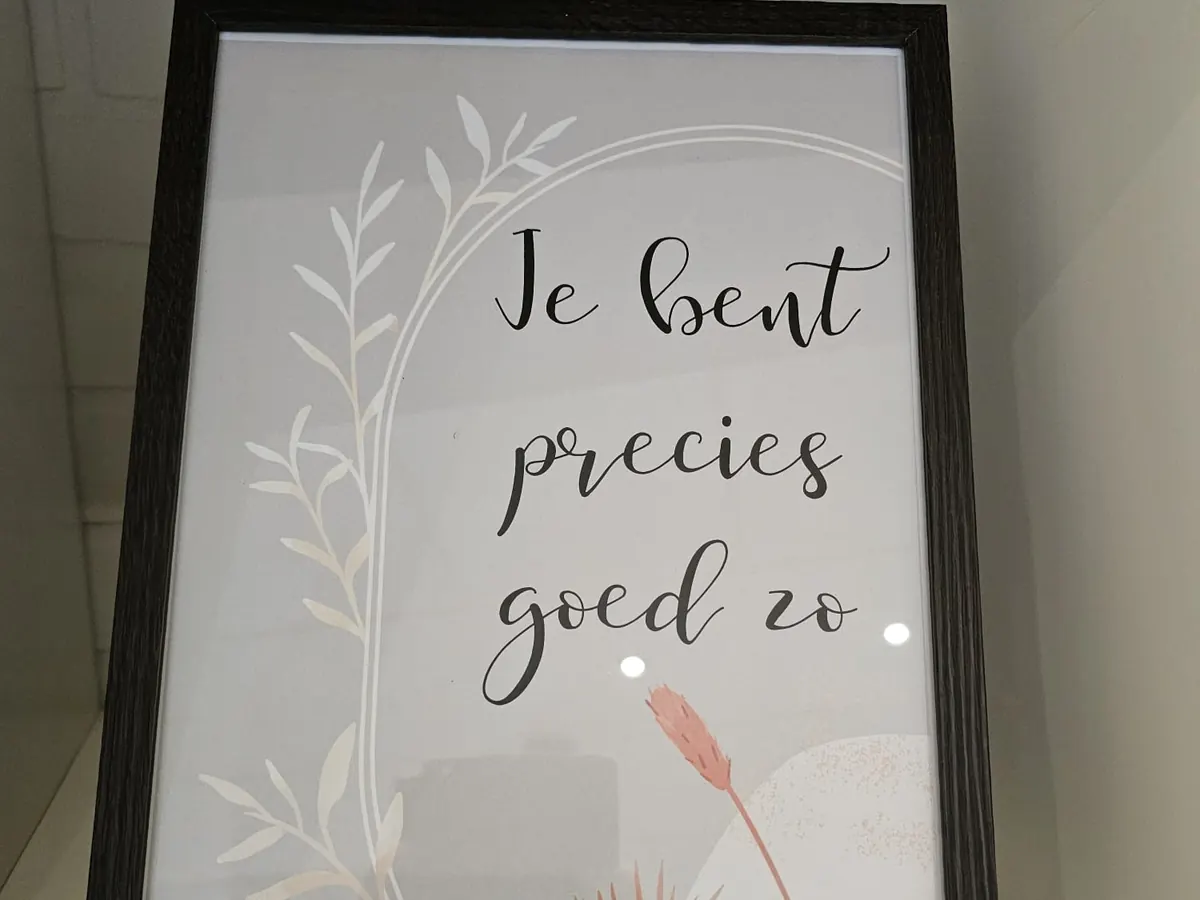 Een poster in een donkere lijst: „Je bent precies goed zo.”