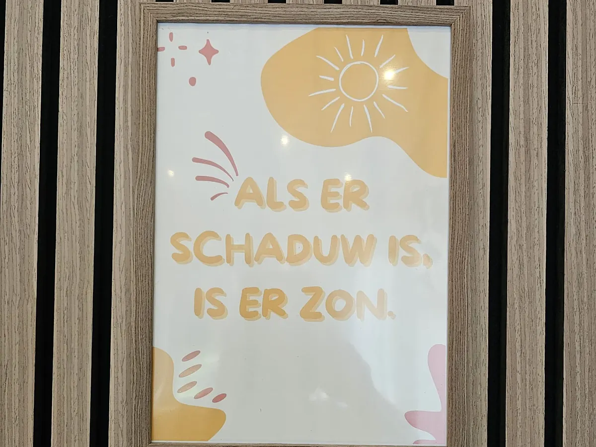 Een poster met een zon: „Als er schaduw is, is er zon.”