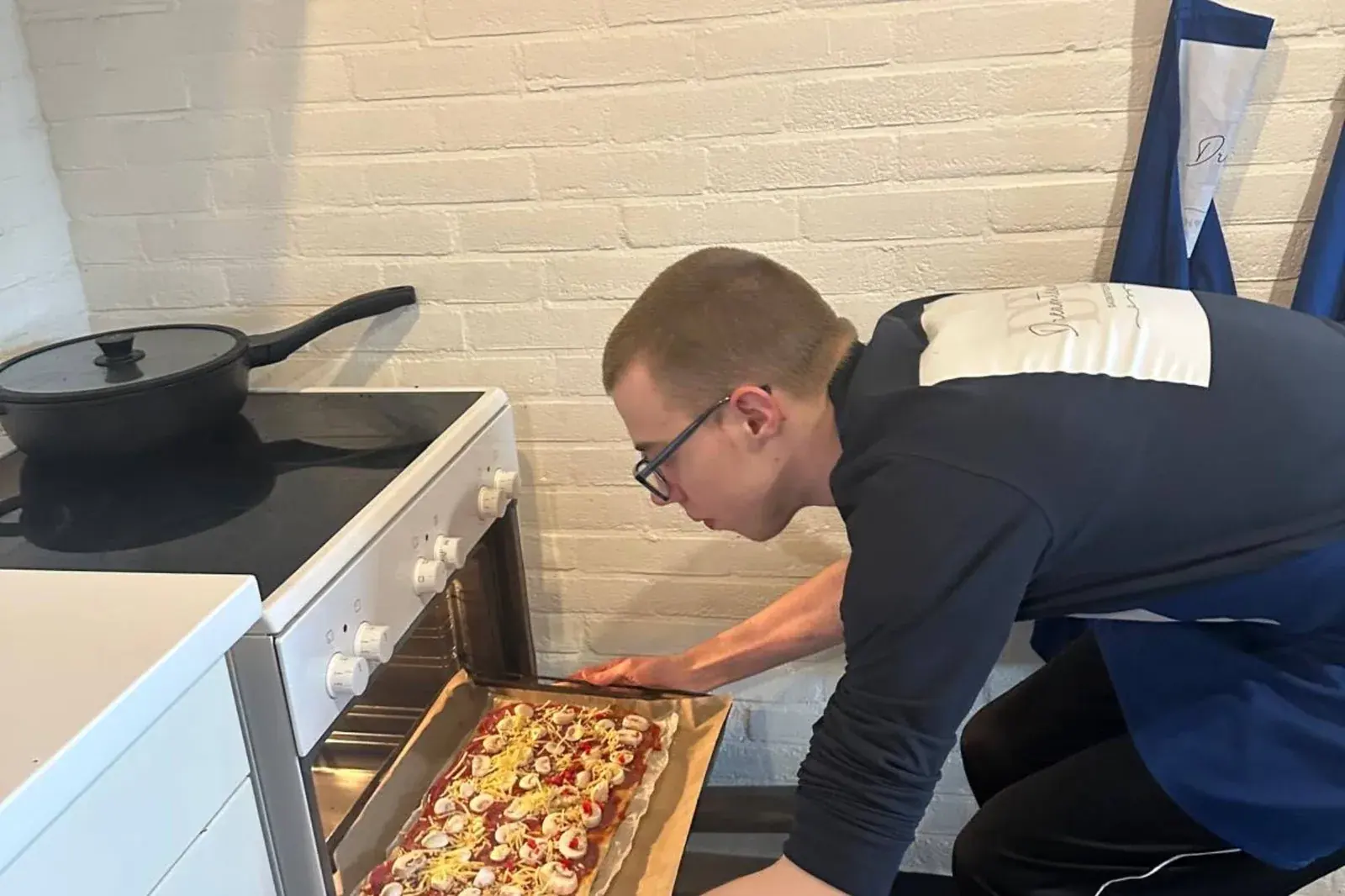 Iemand schuift een plaat met zelfgemaakte pizza in de oven.